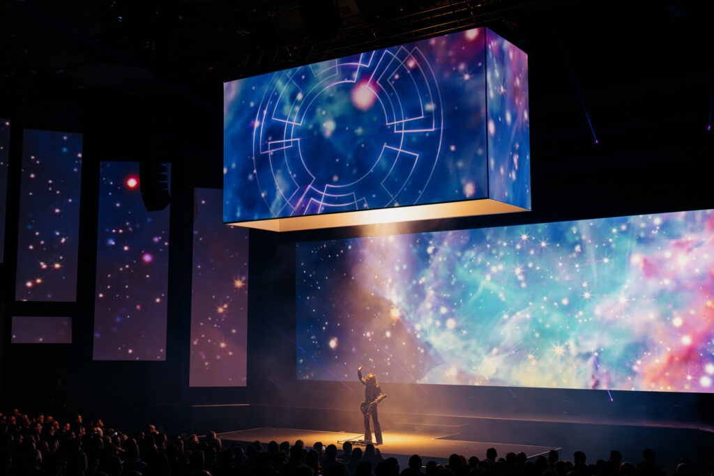 Guitarist performing at a Live Group corporate event, with an elaborate stage setup and lighting creating a high-energy musical experience.