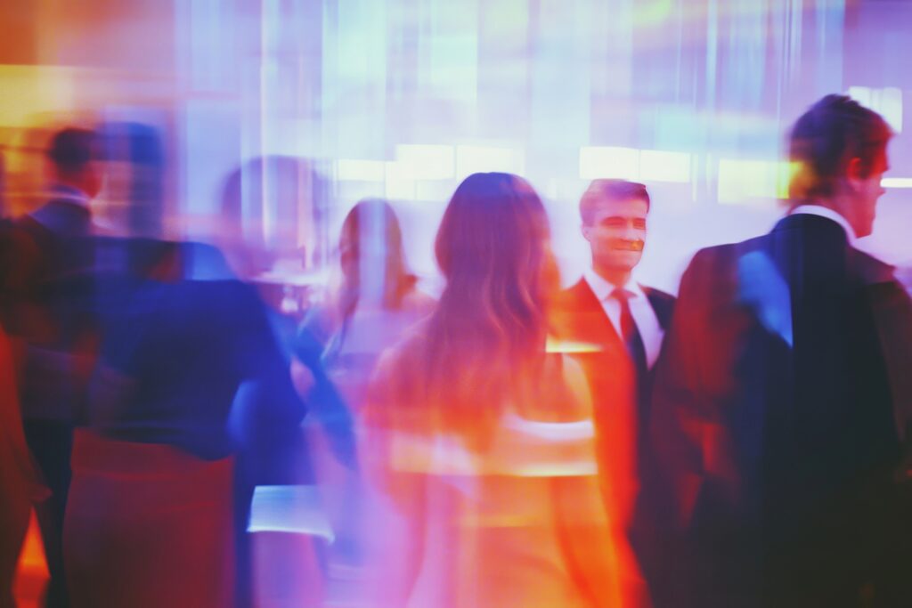 Blurry, stylised image of people at an event, with warm orange and blue tones creating an atmospheric, energetic feel.
