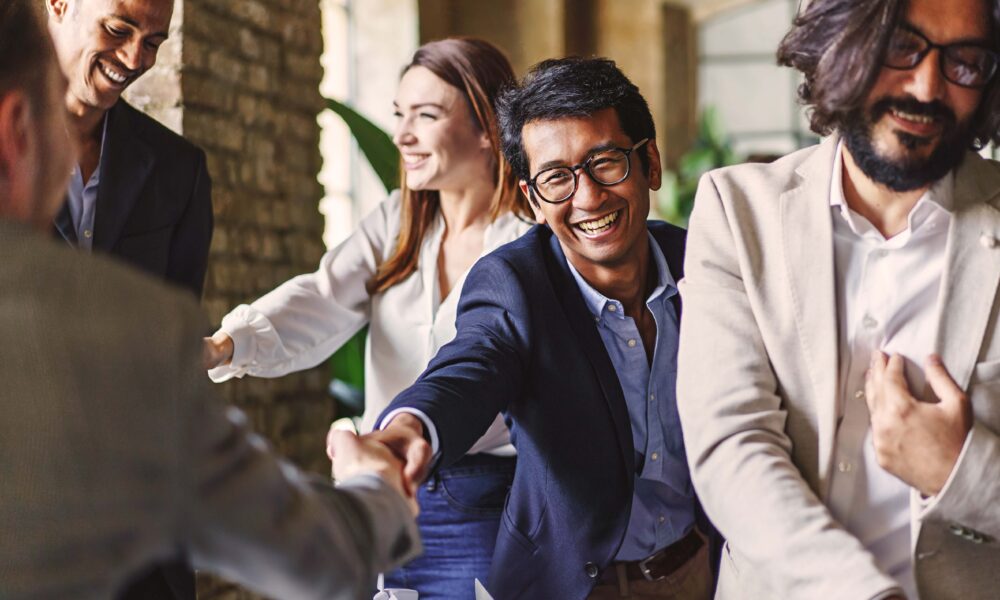 Group of people shaking hands at an event, symbolising genuine human connection and the building of professional relationships