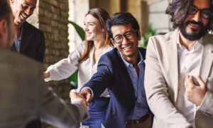 Group of people shaking hands at an event, symbolising genuine human connection and the building of professional relationships