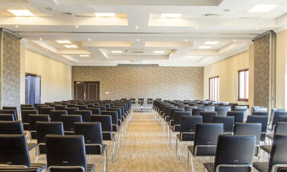 Corporate event space set up with rows of empty chairs facing a stage, ready for attendees