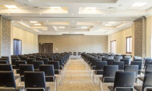 Corporate event space set up with rows of empty chairs facing a stage, ready for attendees