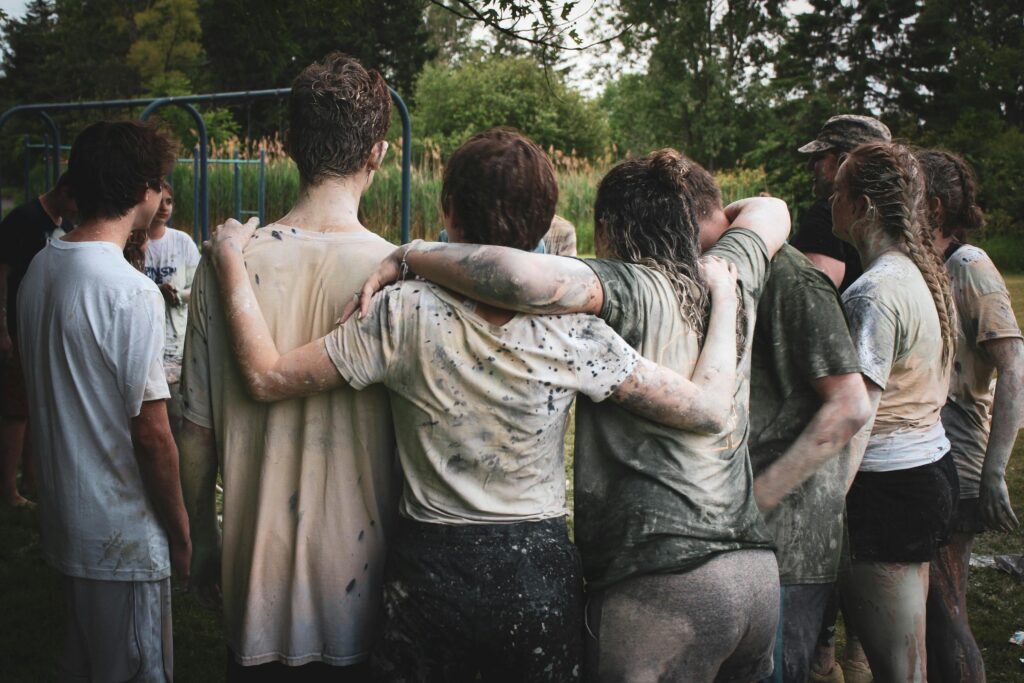 Team building event outdoors with colleagues working together in a muddy challenge to build trust and resilience.