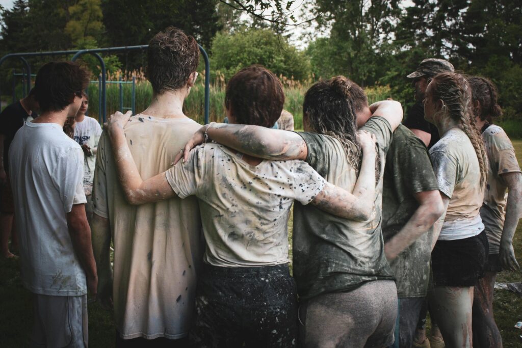 Team building event outdoors with colleagues working together in a muddy challenge to build trust and resilience.