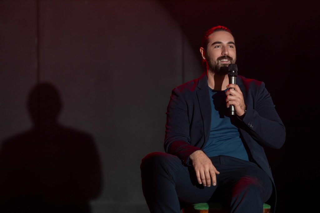 Celebrity speaker on stage at event with dark background