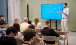 Person speaking at an AI event seminar with audience listening and engaging in discussion.