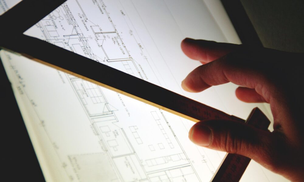 Event planner using a ruler to review a bespoke table layout on an illuminated design desk.