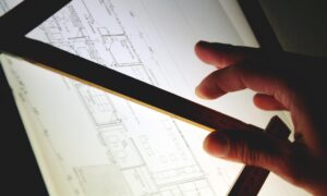 Event planner using a ruler to review a bespoke table layout on an illuminated design desk.