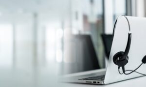 Laptop with a headset draped over it, symbolising a webinar event and online learning setup.