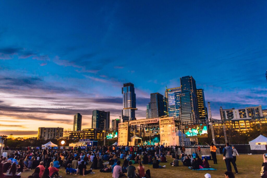 Crowd enjoying a live presentation at the SXSW 2025 outdoor stage, with speakers and performers on stage