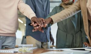 A corporate team putting their hands together in unity, showing why team building is important for building trust and teamwork.