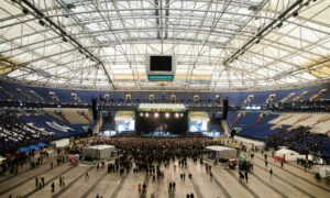 Professional B2B event conference setup featuring stage lighting, large screens and organised seating prepared for delegates.