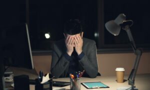 Employee overwhelmed by digital notifications symbolising workplace communication overload.