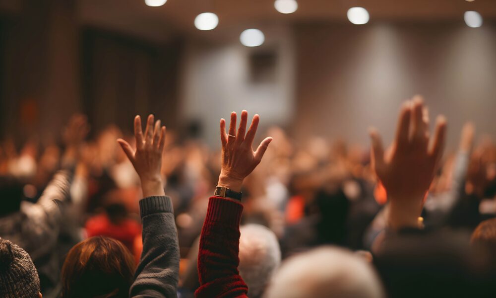 Event attendees with hands up because of personalised event and audience insights.