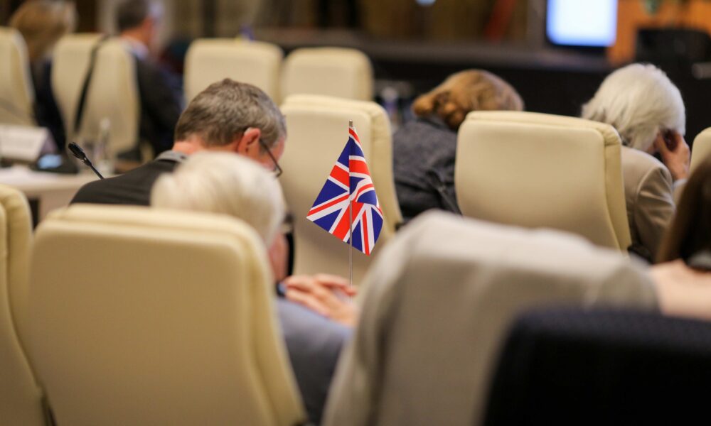 Delegate with UK flag at government event. Successful government event management.