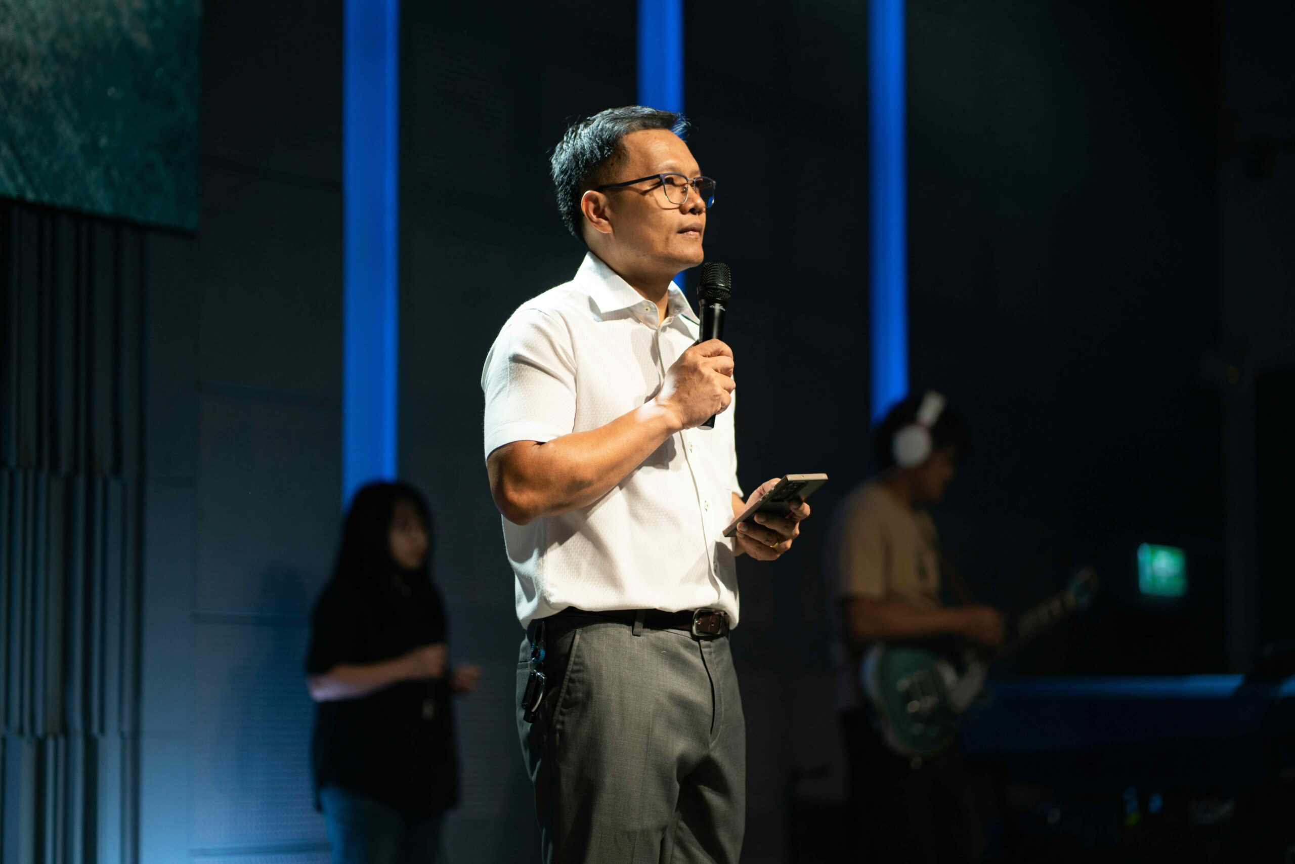 Speaker on stage at a leadership conference delivering a keynote presentation to an audience.