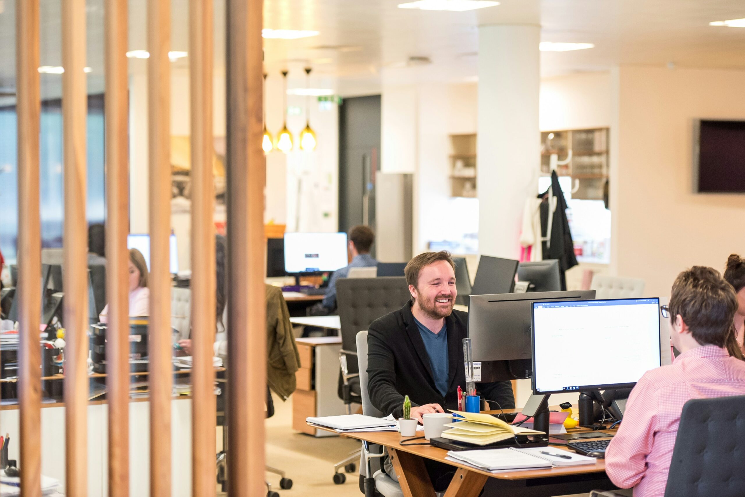Colleagues discussing ideas in a modern office workspace, representing employee communication, collaboration, and effective internal comms in the workplace.