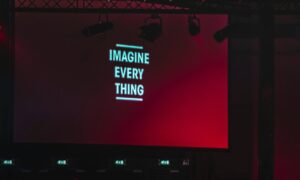 Large presentation slide at a corporate event displaying thought-provoking leadership communication and visual storytelling content to an engaged audience.