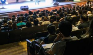 Audience paying attention to speaker in a session hall.