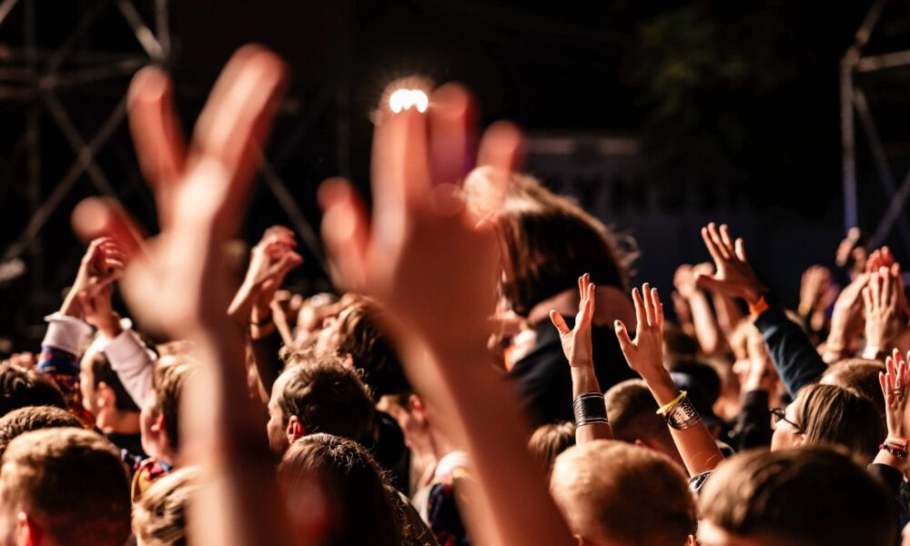 Audience at event with hands up to signify high levels of engagement.